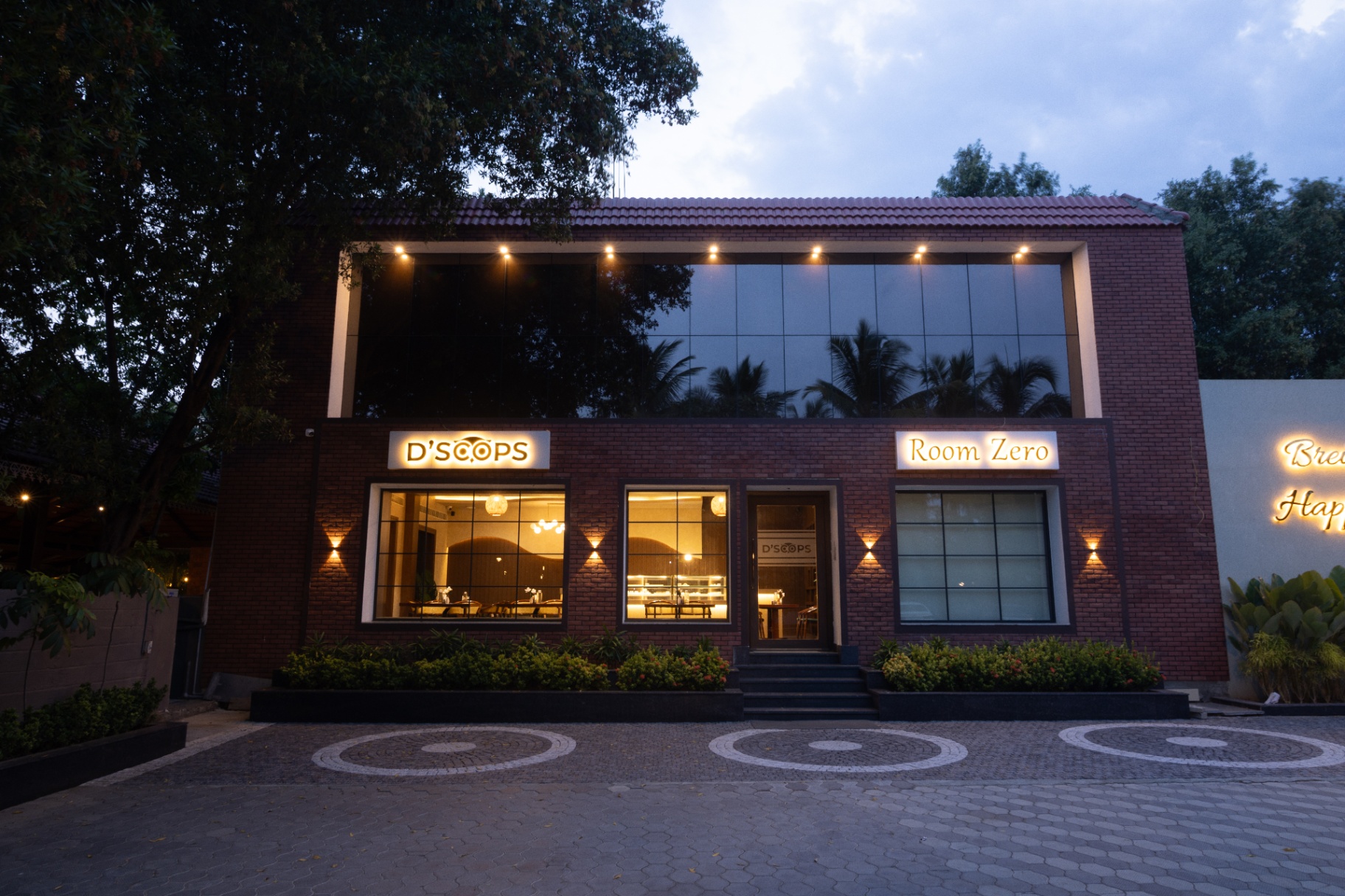 D'Scops Café evening front view with warm lights and glass frontage at D'Wayfarer Inn